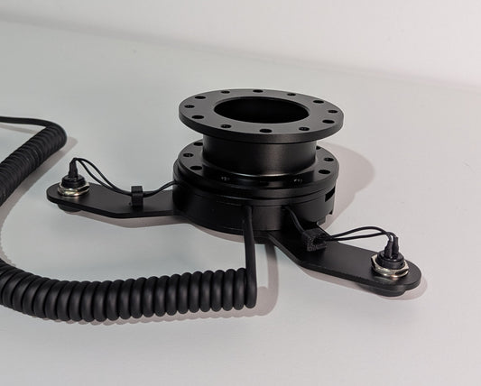 Rear view of the JC wheel hub without the JC front plate The wheel hub has a bottom 2 button bracket with black buttons mounted. The hub has a black coiled cable.