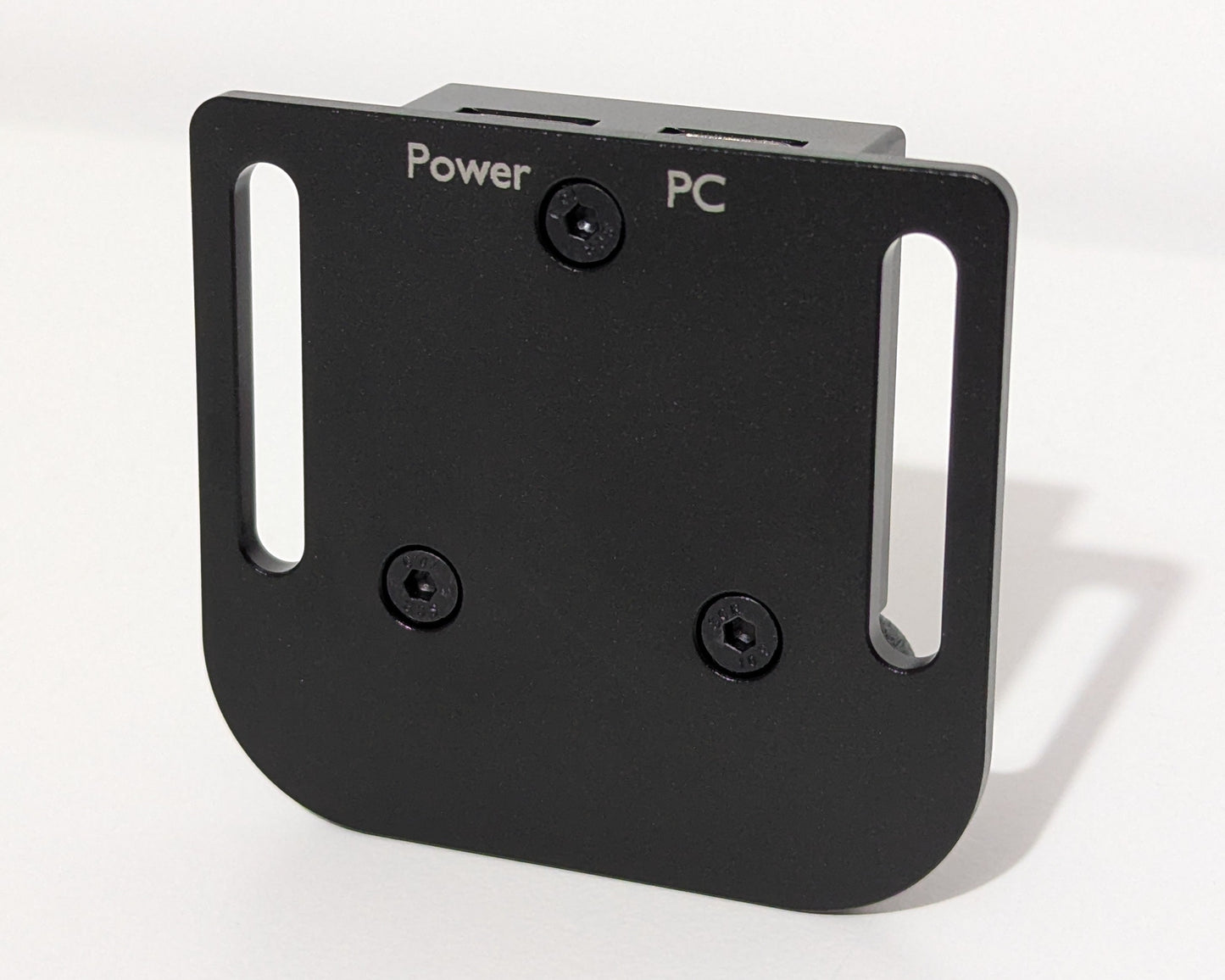 An image showing the underside of a small black device. The words Power and PC are engraved in the finish to indicate which port is used for which connection for the JCSS USB Power Injector