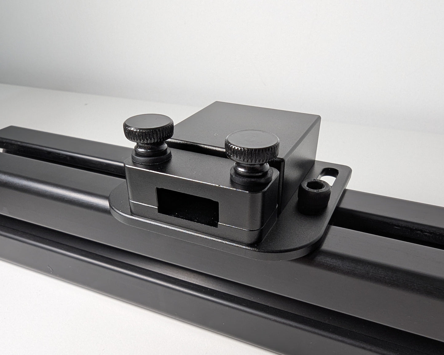 Close-up of the JC USB Power Injector mounted to black 4040 profile.  The USB power injector is a black box attached to the profile with 2 bolts.  The front view shows the two black thumbscrews and hold down for securely mounting a cable.