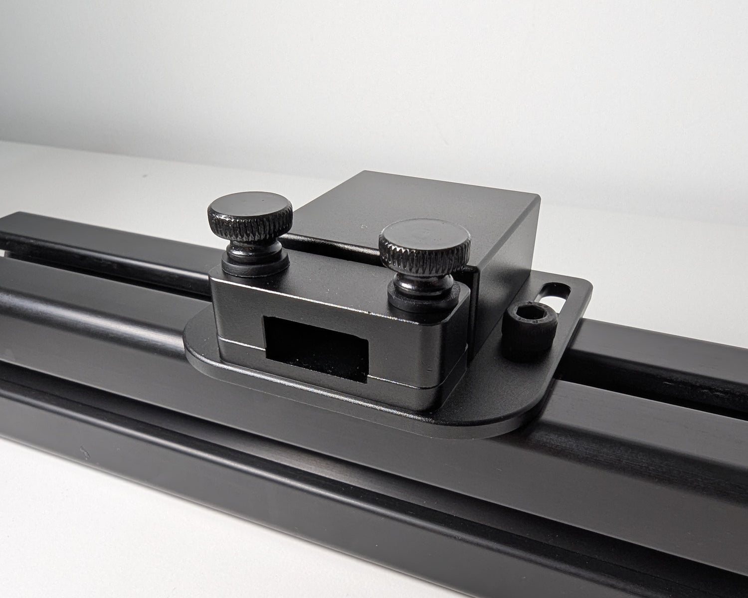 Close-up of the JC USB Power Injector mounted to black 4040 profile.  The USB power injector is a black box attached to the profile with 2 bolts.  The front view shows the two black thumbscrews and hold down for securely mounting a cable.