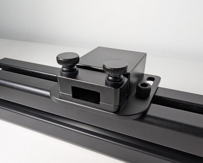 Close-up of the JC USB Power Injector mounted to black 4040 profile.  The USB power injector is a black box attached to the profile with 2 bolts.  The front view shows the two black thumbscrews and hold down for securely mounting a cable.