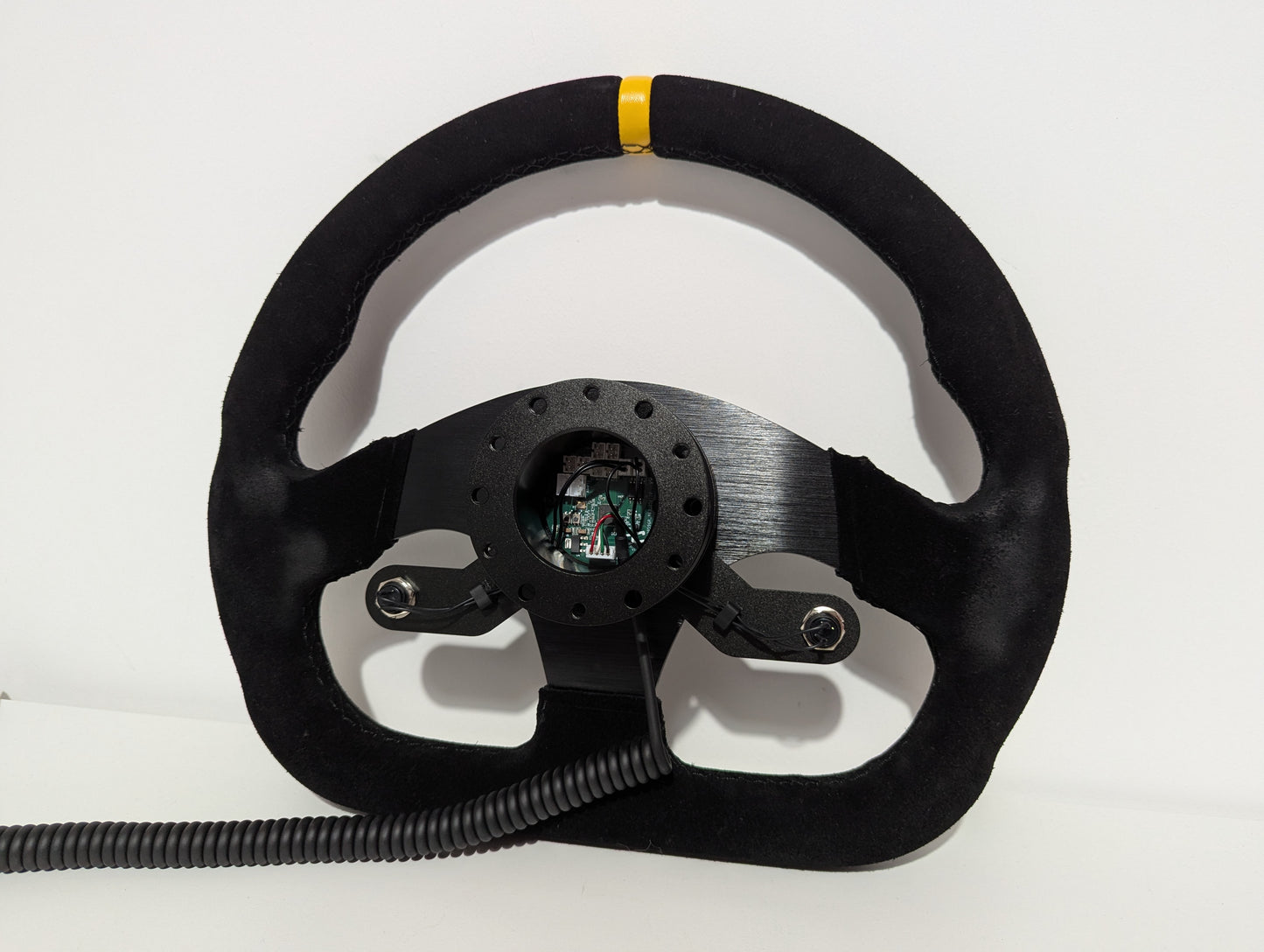 Black steering wheel on a white background  The wheel has a JC wheel hub with a bottom 2 button bracket with black buttons mounted.  The hub has a black coiled cable. The main PCB is visible in the back of the hub.